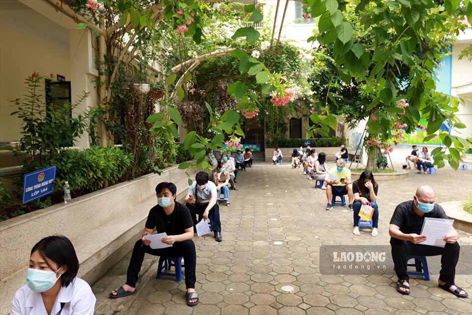 Người dân xếp hàng, đảm bảo giãn cách khi đến tiêm tại điểm Trường tiểu học Thanh Xuân Trung.