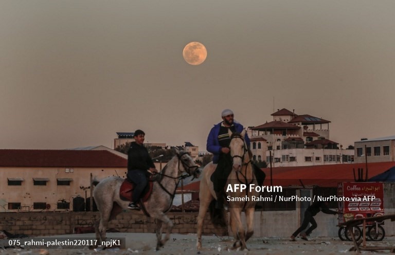 Người Palestine cưỡi ngựa ở bãi biển khi Trăng Sói mọc trên thành phố Gaza. Ảnh: AFP