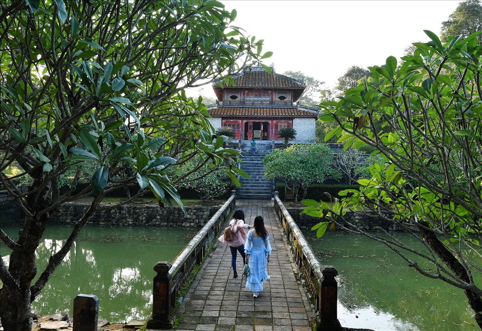 Trước lầu Minh Lâu. Minh Lâu trong lăng Minh Mạng Huế có nghĩa là lầu sáng - nơi để nhà vua suy tư vào những đêm trăng thanh gió mát. Tòa nhà có kiến trúc hình vuông, hai tầng, tám mái nằm trên quả đồi Tam Đài Sơn và sau lưng là vườn hoa chữ Thọ. Minh Lâu được trang trí đẹp mắt, mang đậm hơi thở của Nho Giáo và triết lý nhân sinh.