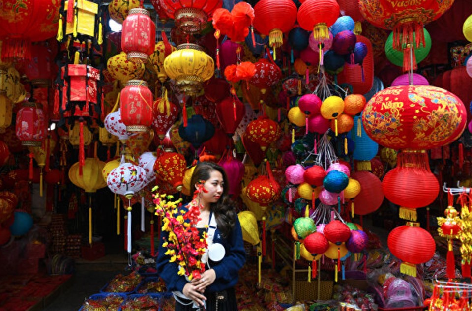 Tạo dáng trước cửa hàng bán đồ trang trí Tết ở phố cổ Hà Nội. Ảnh: AFP