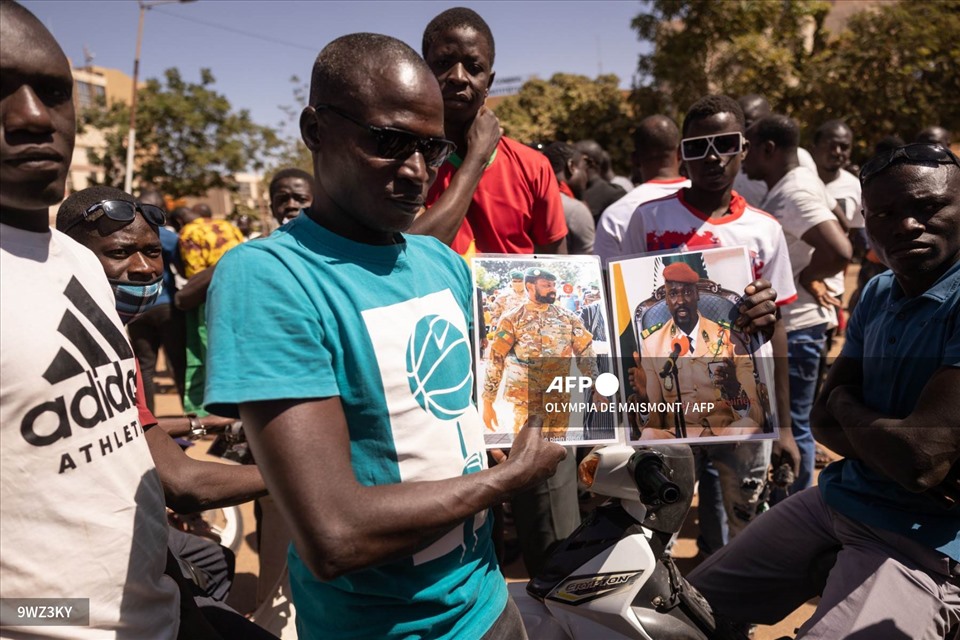 Một người đàn ông cầm chân dung Tổng thống lâm thời Mali Assimi Goita (trái) và thủ lĩnh quân đội Guinea, Đại tá Mamady Doumbouya (phải) trong khi mọi người tập trung tại quảng trường Nation để ủng hộ quân đội Burkina Faso ở Ouagadougou vào ngày 24.1.2022. Ảnh: AFP