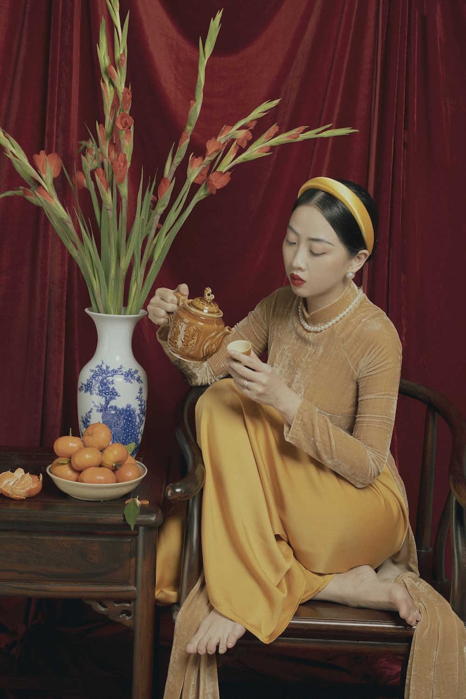 Lấy cảm hứng từ hình ảnh những người phụ nữ xưa, tà áo dài vàng mà MC Hà Trinh lựa chọn cùng với bối cảnh bàn trà, ấm nước, bình hoa lay-ơn đỏ… cho người xem cảm giác mộc mạc, gần gũi.
