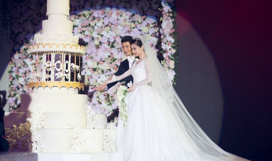 Huỳnh Hiểu Minh và Angela Baby cắt chiếc bánh cưới khổng lồ. Ảnh: Sina.