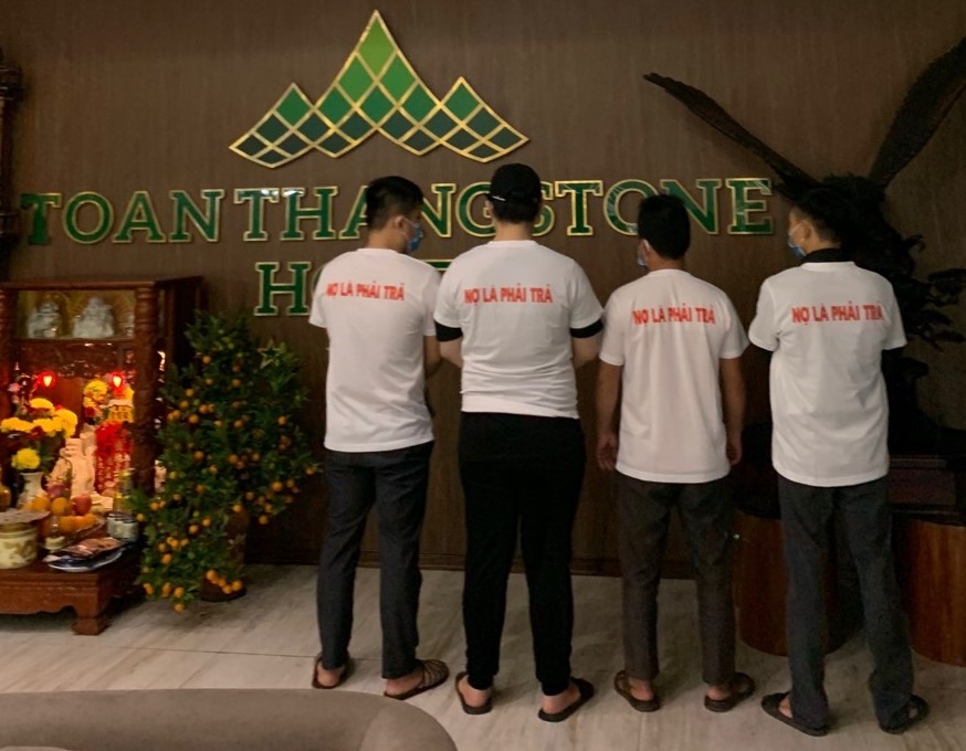 Nhóm người mặc áo phông có in nội dung đòi nợ đến trước khách sạn Toàn Thắng. Ảnh: PL