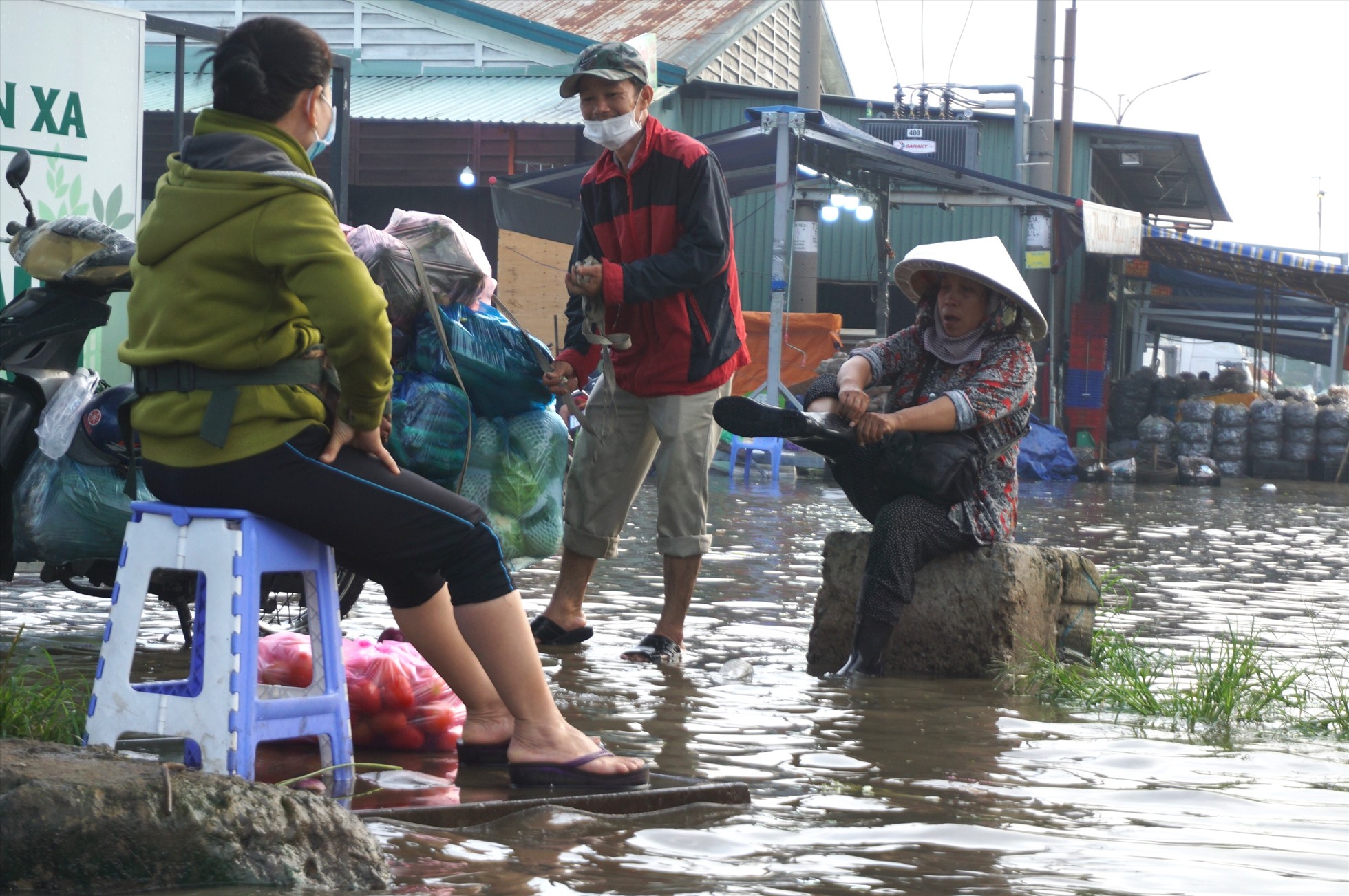Một số người chuẩn bị sẵn đôi ủng để lội nước ngập. Người dân buôn bán tại chợ cho biết khu vực này thường xuyên bị ngập nước do triều cường nhưng đây là trận ngập lớn nhất trong năm nay.
