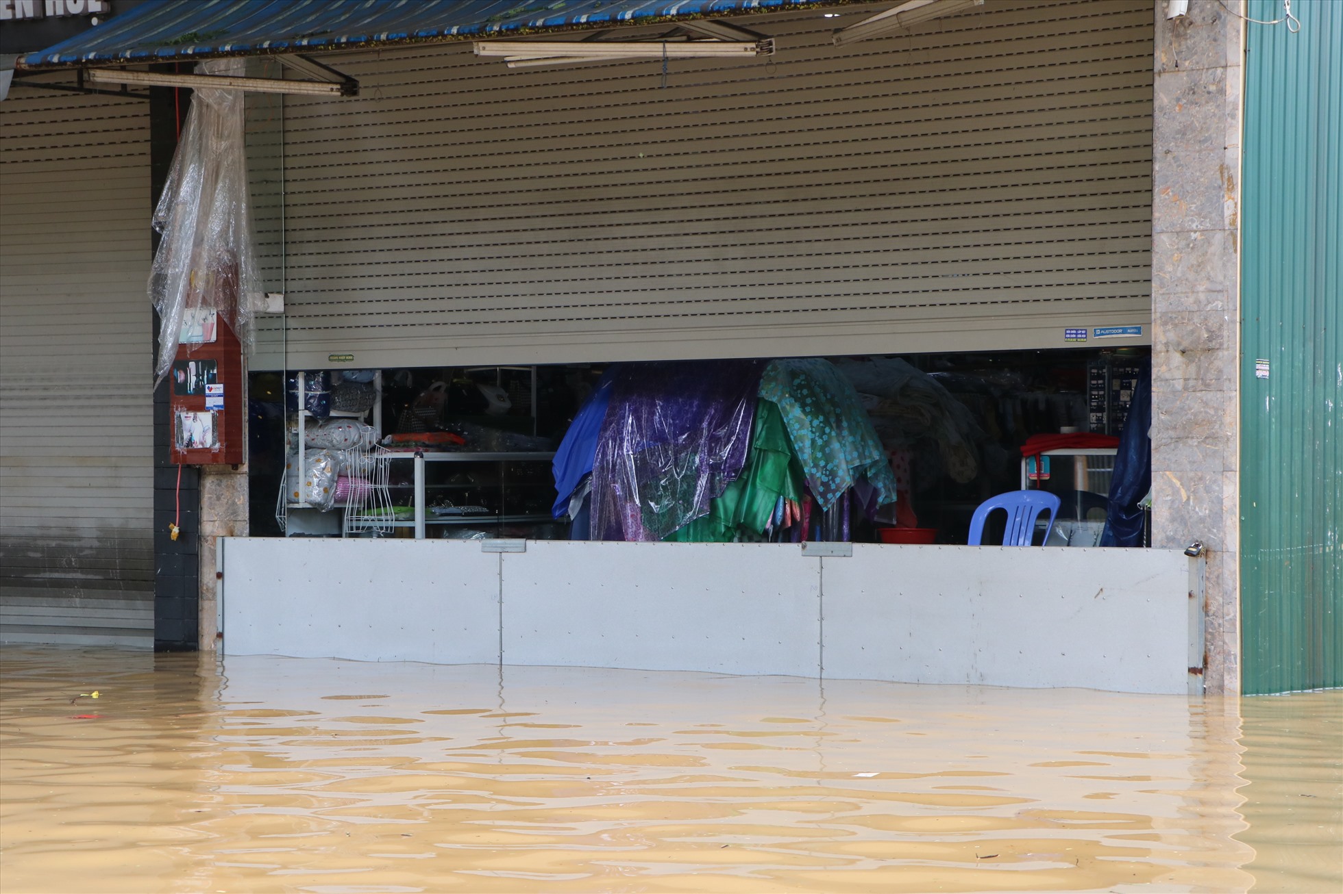 Nhiều hàng quán của người dân dùng các tấm chắn trước cửa để tránh các đợt sóng nước từ đường đánh vào nhà.