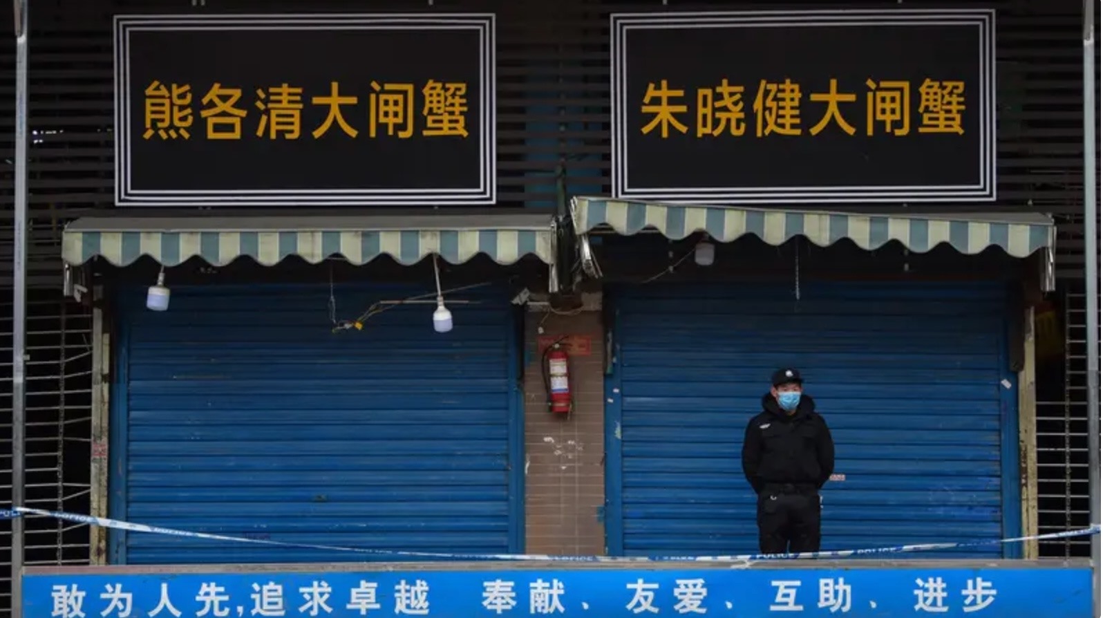 Một nhân viên bảo vệ đứng bên ngoài Chợ bán buôn hải sản Huanan, nơi phát hiện COVID-19 lần đầu tiên ở Vũ Hán. Ảnh: AFP