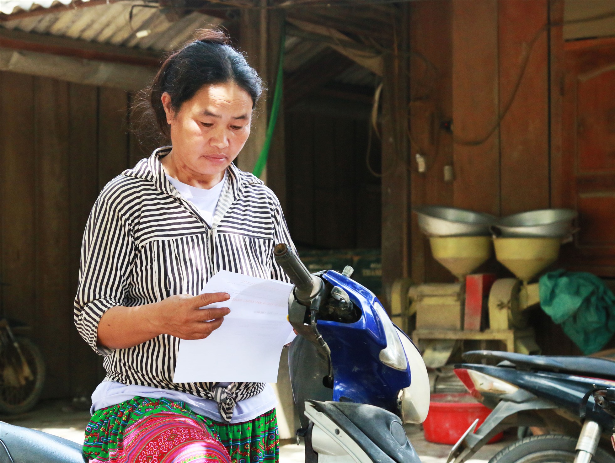 Một người phụ nữ đang nghiên cứu thông tin về các khoản bồi thường, di dời về khu tái định cư mới của chính quyền địa phương.