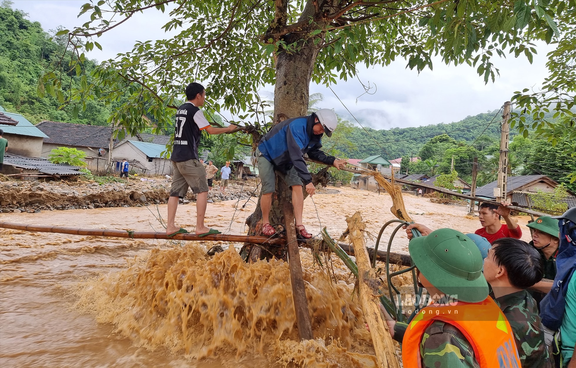 Lực lượng chức năng cùng người dân phải bắc cây ngang dòng nước lũ, để giải cứu những người bị mắc kẹt.