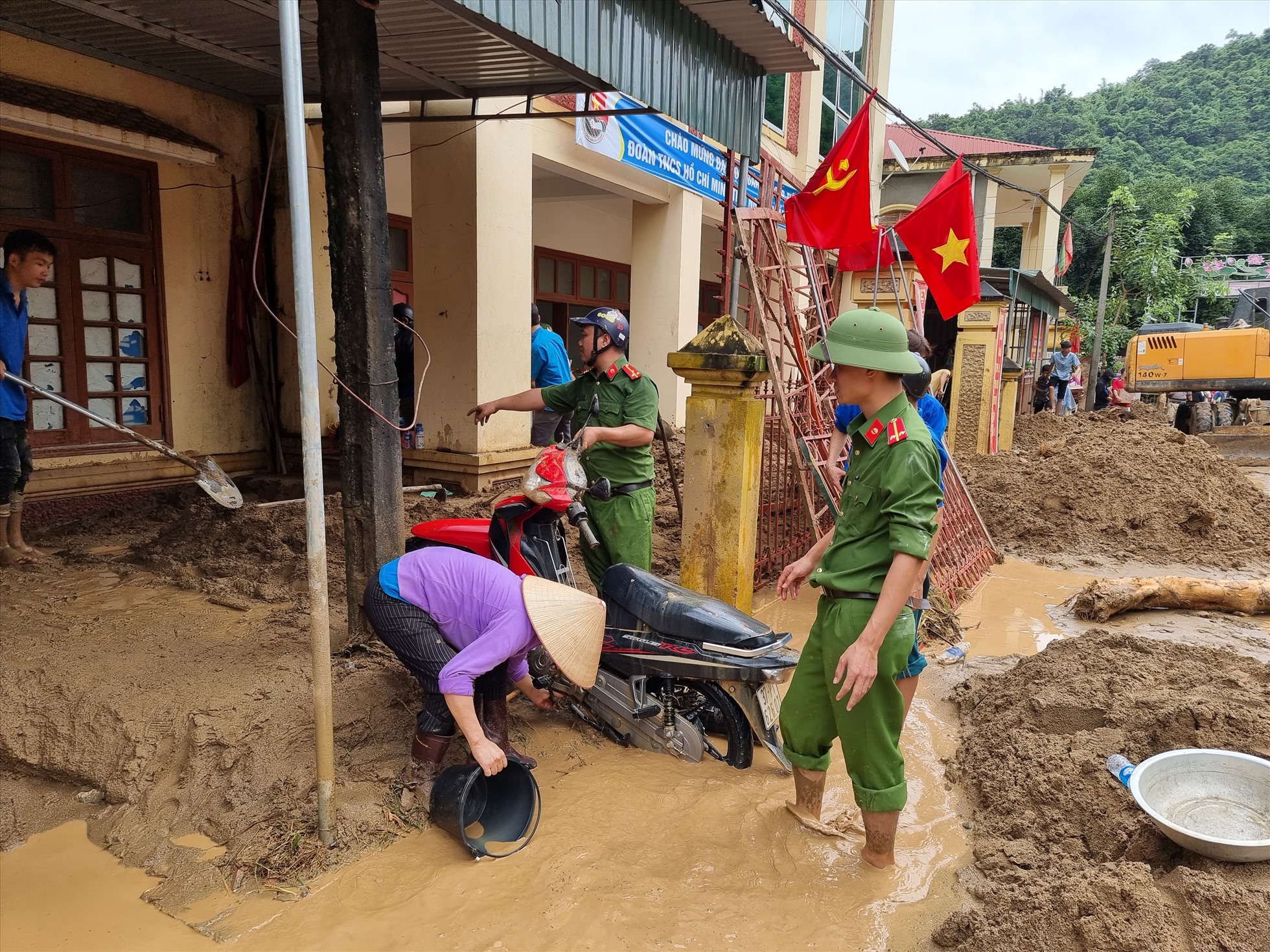 Cán bộ công an giúp dân “giải cứu” một xe máy bị bùn vùi lấp