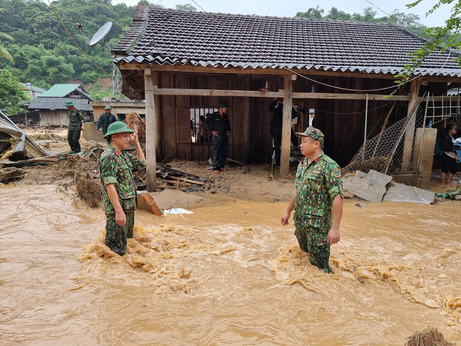 Bộ đội đứng giữa dòng nước lũ tại bản Sơn Hà - xã Tà Cạ  để giúp người dân đi qua an toàn.