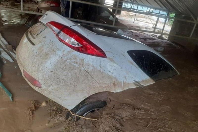 Một ô tô tại thị trấn Mường Xén bị bùn đất do cơn lũ vùi lấp. Ảnh: NA