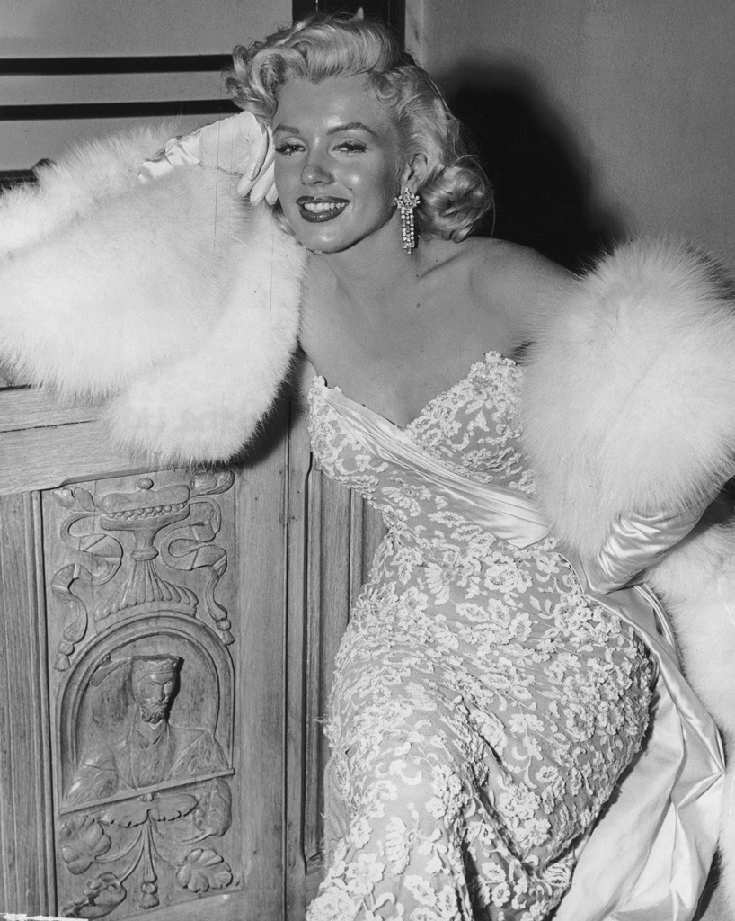 Năm 1953, Marilyn Monroe tham dự lễ công chiếu phim “How to marry a millionaire“. Cô diện váy quây ngực sexy do  William Travilla thiết kế, đeo khuyên tai kim cương và quấn khăn choàng bông. Nụ cười rạng rỡ cùng vóc dáng gợi cảm của nữ diễn viên tạo nên khoảnh khắc đẹp như tranh vẽ. Ảnh: AP.