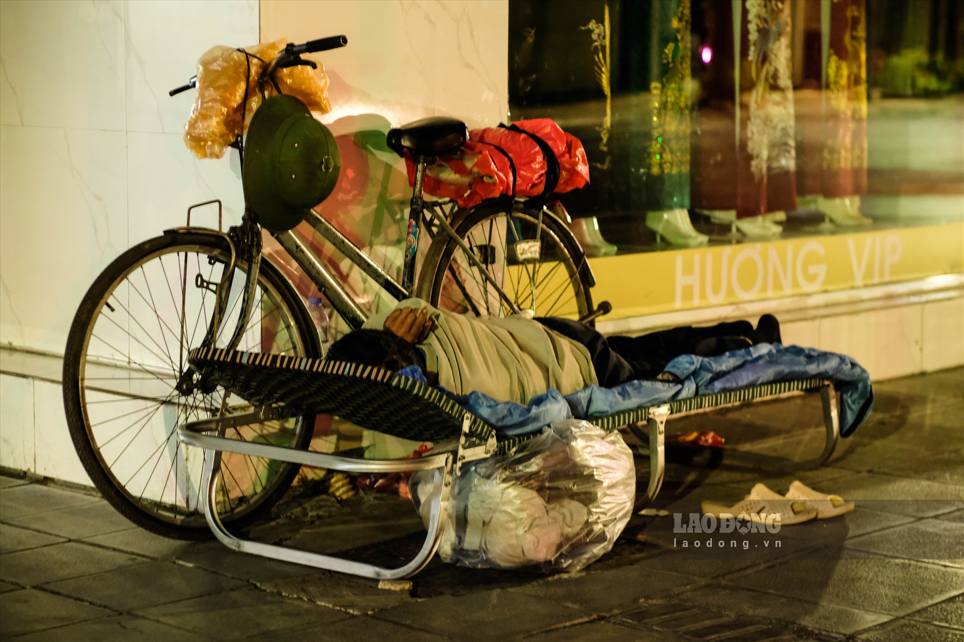 Người vô gia cư nằm ngủ ngon lành bên lề đường, trên người chỉ khoác một tấm chăn mỏng để chắn gió. Cuộc sống “màn trời chiếu đất” vốn đã khó khăn, nay lại càng chồng chất khó khăn vì giá rét.
