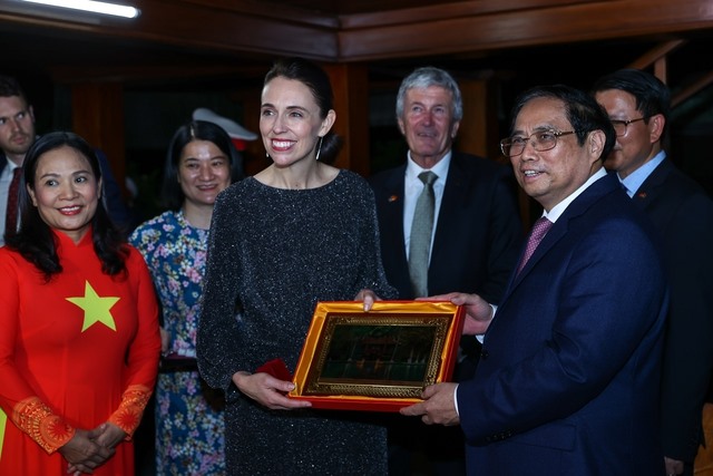 Thủ tướng Phạm Minh Chính tặng Thủ tướng New Zealand bức tranh sơn mài Nhà sàn Bác Hồ. Ảnh: VGP