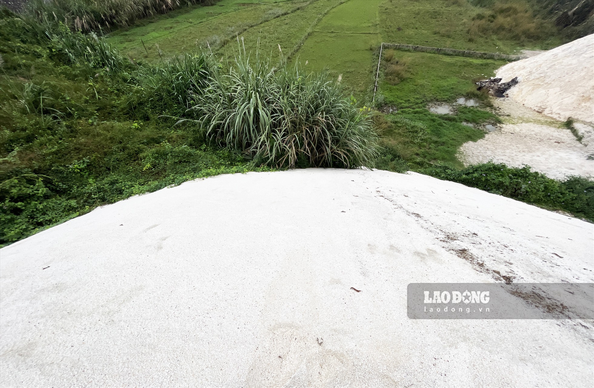 Một phần bãi tập kết đã tràn ra ngoài khu vực hành lang KCN khiến bột đá chảy xuống đất ruộng. Ảnh: Nguyễn Tùng.