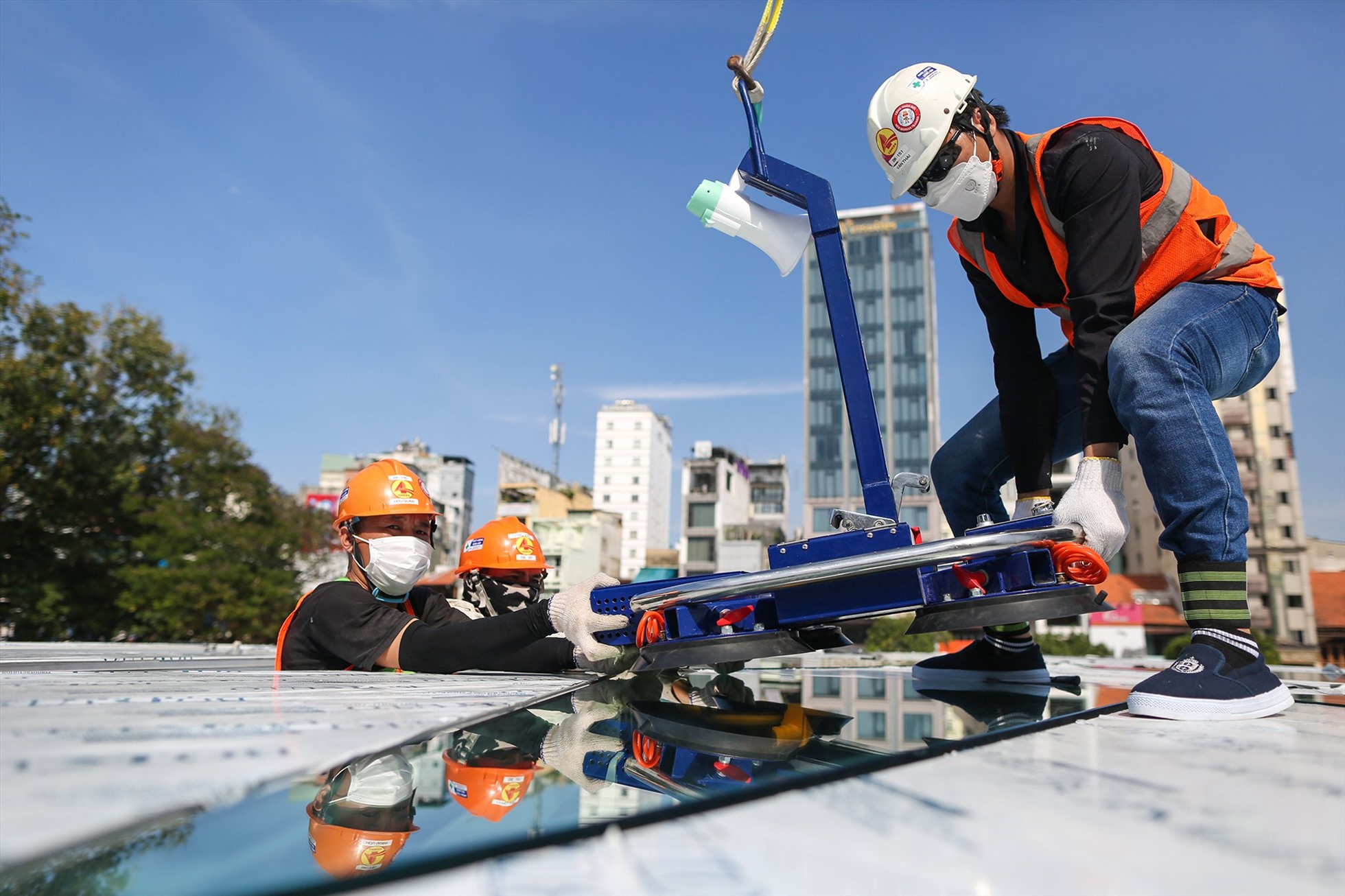 Công nhân dùng thiết bị chuyên dụng để đưa đến lắp đặt trên mái vòm giếng trời.