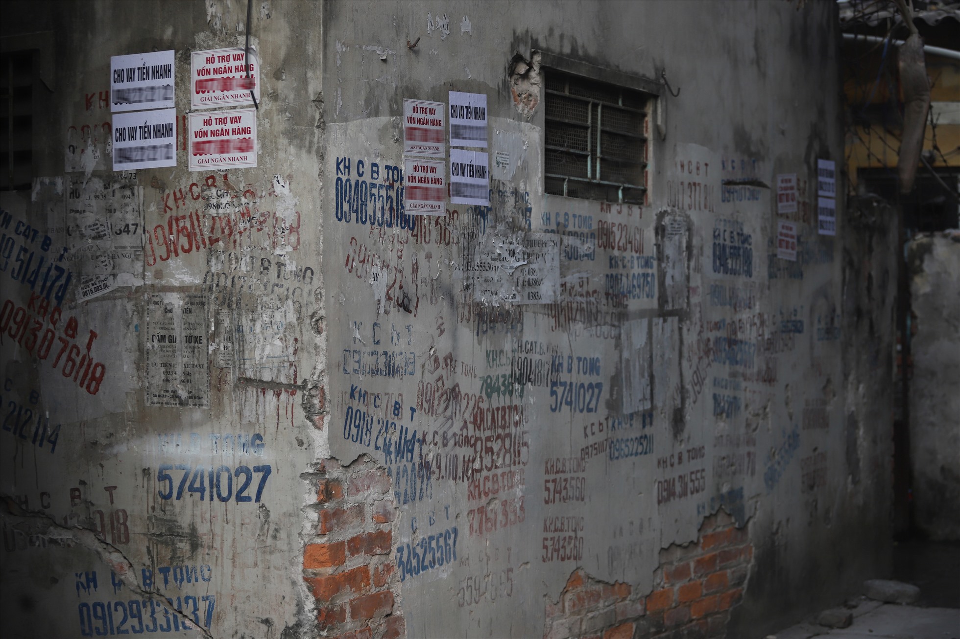 Những tờ quảng cáo dán nham nhở trên bờ tường nhà dân ở TP Hà Nội.
