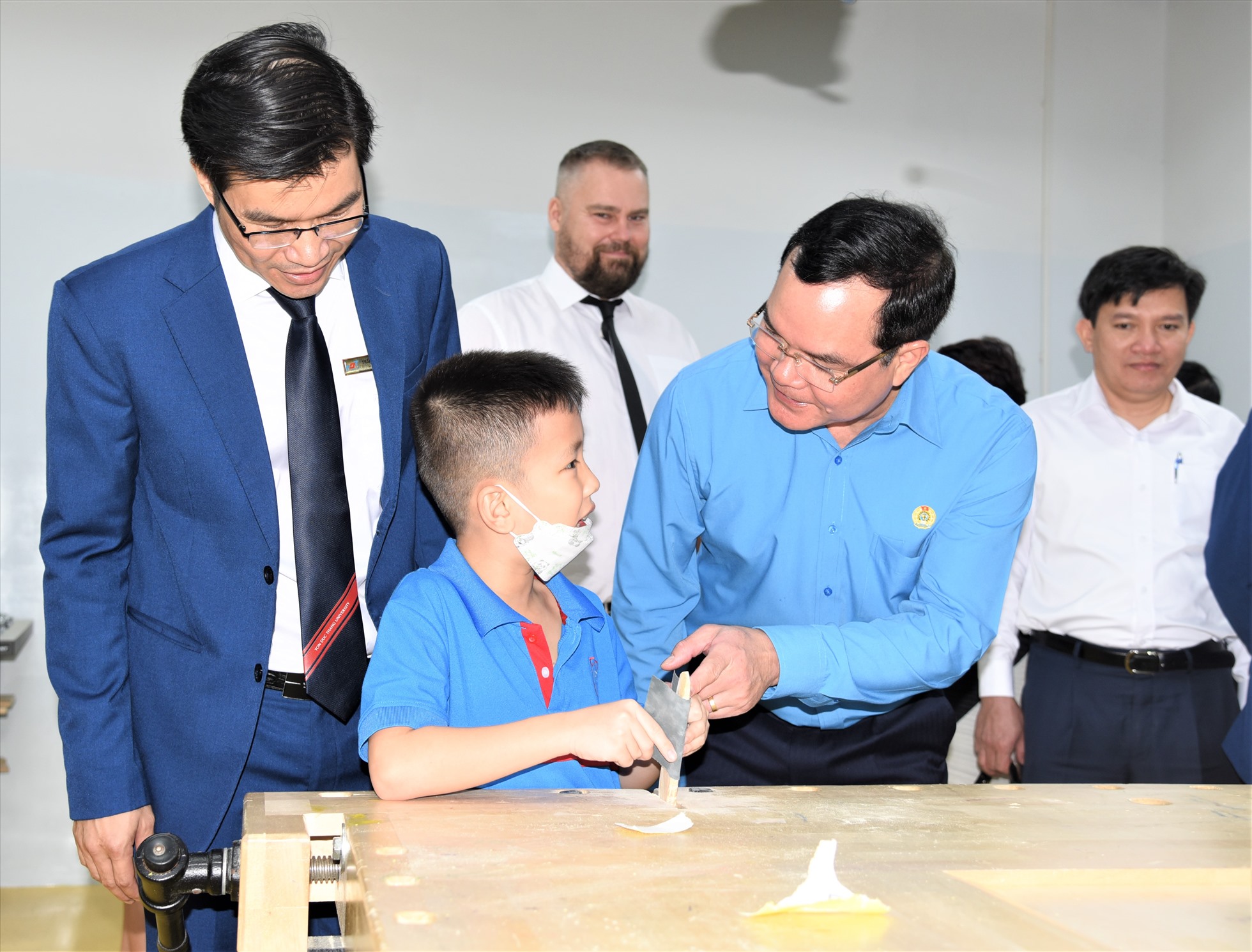Chủ tịch Tổng LĐLĐ Việt Nam (thứ hai từ phải qua) hỏi thăm học sinh Trường Việt Nam - Phần Lan trong giờ thực hành nghề mộc. Ảnh: Nam Dương