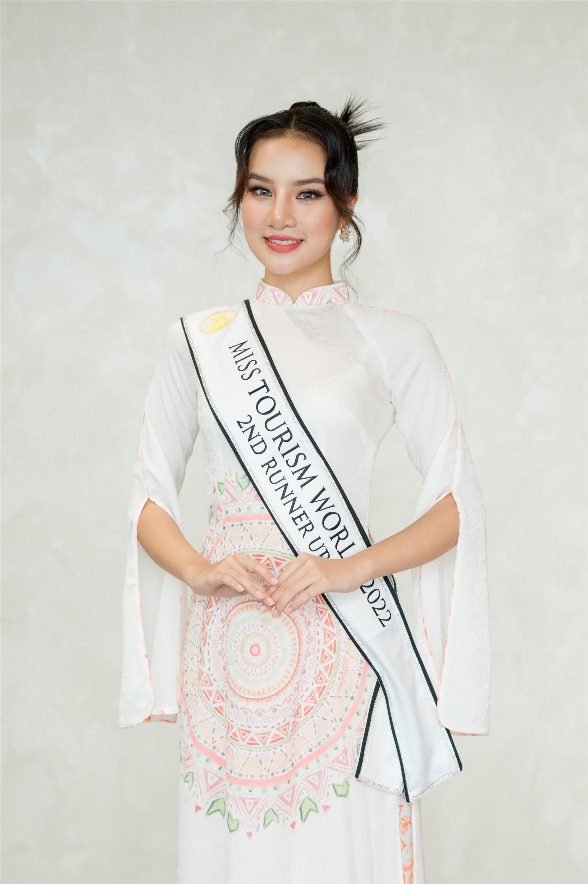 Á hậu 2 Miss Tourism World 2022 Hương Ly e ấp làm duyên với bộ cánh in họa tiết hoa nắng gam đỏ.  Hương Ly cho biết, hơn một tháng đồng hành cùng các thí sinh Hoa hậu Du lịch Thế giới, với vai trò là người đẹp nước chủ nhà, cô đã có dịp làm hướng dẫn viên cho bạn bè quốc tế.  “Tôi cùng các thí sinh đã có những trải nghiệm thú vị, khám phá nhiều vùng đất mới, tìm hiểu văn hóa các dân tộc Việt Nam. Đây là lúc chúng ta hồi phục ngành du lịch sau Covid-19.  Qua cuộc thi này tôi hy vọng các người đẹp và bạn bè quốc tế cảm nhận được vẻ đẹp thiên nhiên cũng như hình ảnh nồng hậu, hiếu khách của người dân Việt Nam“, Hương Ly nói.  Hương Ly mới 20 tuổi, hiện là sinh viên ngành Sư phạm Anh - Nhật, Đại học Hải Phòng. Cô từng đoạt Á hậu 1 cuộc thi Hoa hậu Hoàn cầu Việt Nam 2022.