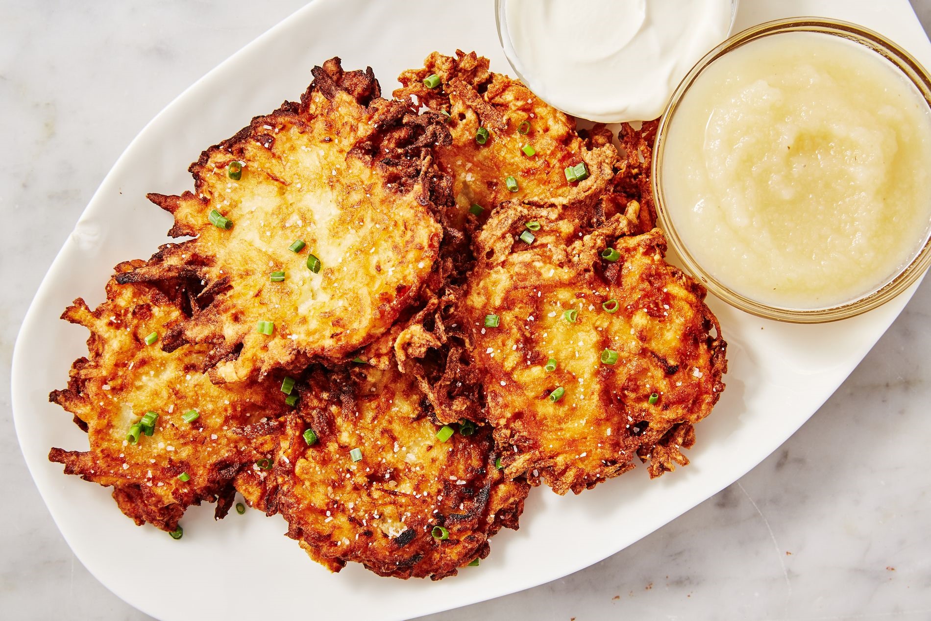 Ban đầu Latkes được làm từ pho mát chiên trong dầu hoặc bơ hạt anh túc, và dùng với mứt trái cây chứ không phải khoai tây như bây giờ. Ảnh: Delish.