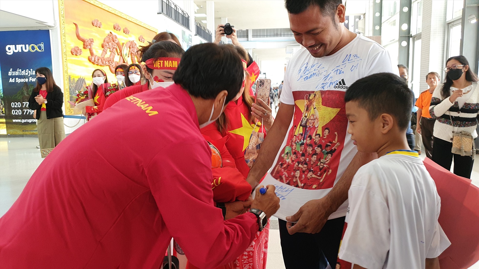 Đội tuyển Việt Nam ký tặng người hâm mộ tại sân bay Viêng Chăn - Lào. Ảnh: VFF