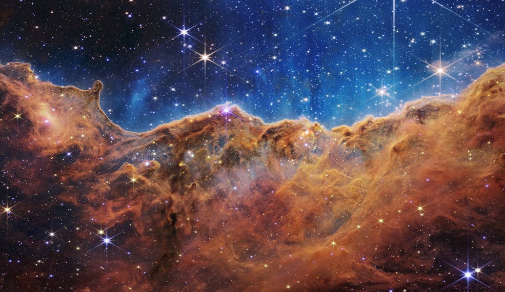 Phong cảnh gồm “núi” và “thung lũng” lốm đốm những ngôi sao lấp lánh này thực ra là rìa của một vùng hình thành sao trẻ gần đó có tên là NGC 3324 trong Tinh vân Carina. Bức ảnh được chụp bằng ánh sáng hồng ngoại của kính viễn vọng không gian James Webb mới của NASA lần đầu tiên cho thấy các khu vực hình thành sao không thể nhìn thấy trước đây. Ảnh: NASA