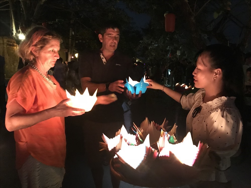Du khách quốc tế thả đèn trong Lễ hội Nguyên tiêu ở Hội An. Ảnh: Tường Minh