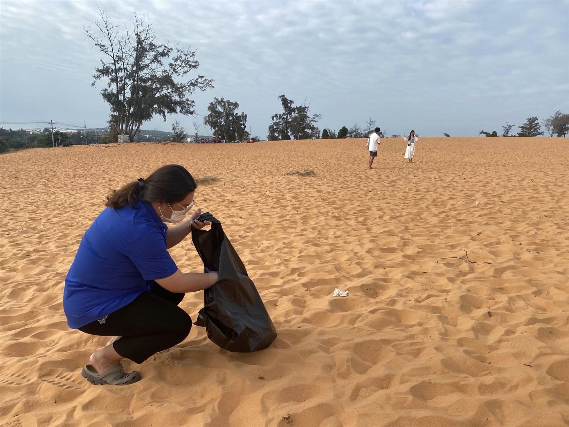 Nữ đoàn viên nhặt rác trên đồi cát Mũi Né. Ảnh: Nguyên Vũ