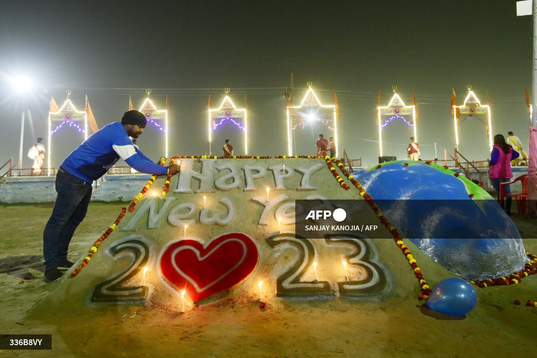 Một thanh niên thắp nến trên tác phẩm điêu khắc cát để chào đón năm mới tại khu vực Sangam, nơi hợp lưu của sông Hằng, Yamuna và Saraswati ở Prayagraj, Ấn Độ. Ảnh: AFP