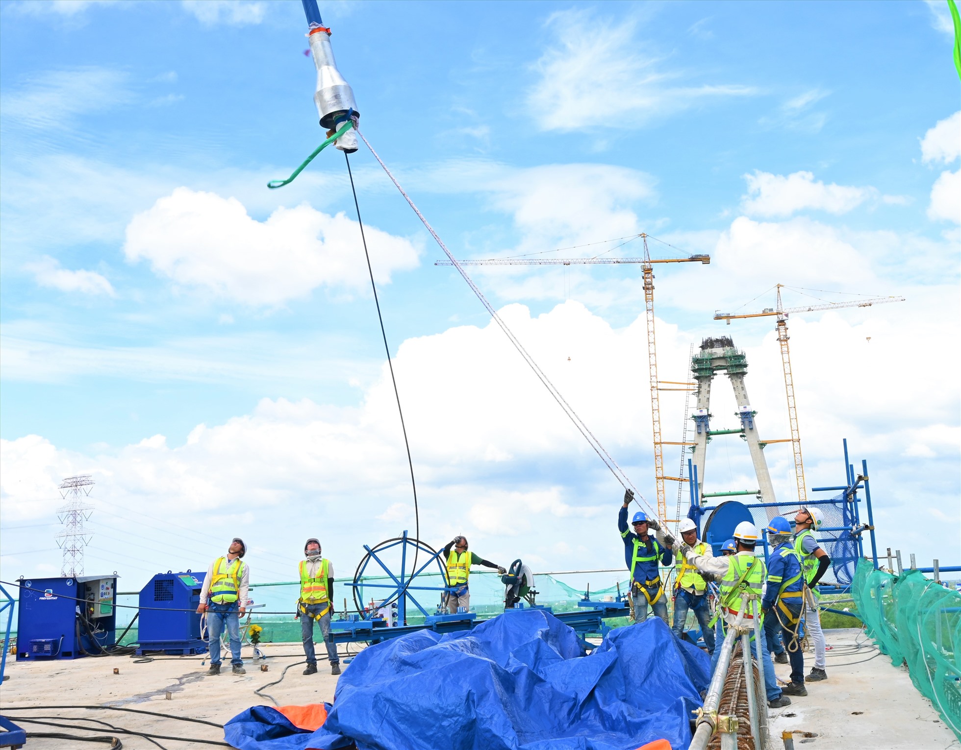 Công nhân thi công căng dây cáp đầu tiên tại tháp trụ T16 dự án công trình cầu Mỹ Thuận 2. Ảnh: Thành Nhân.