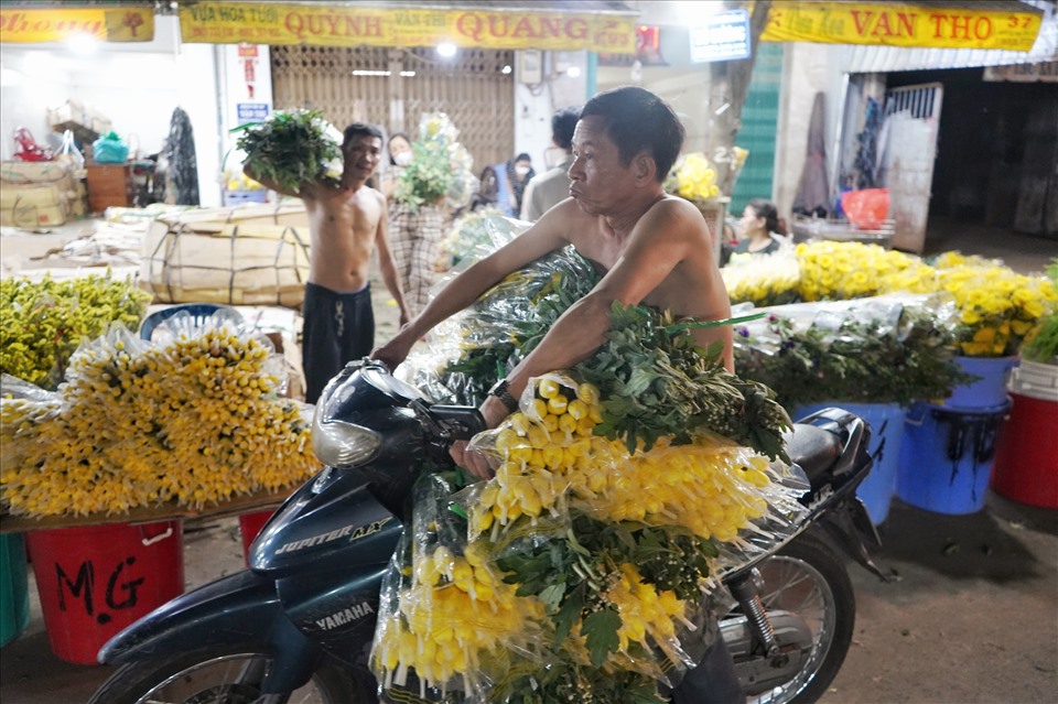 Nhân viên bốc xếp tất bật vận chuyển hoa từ ngoài vào trong chợ.
