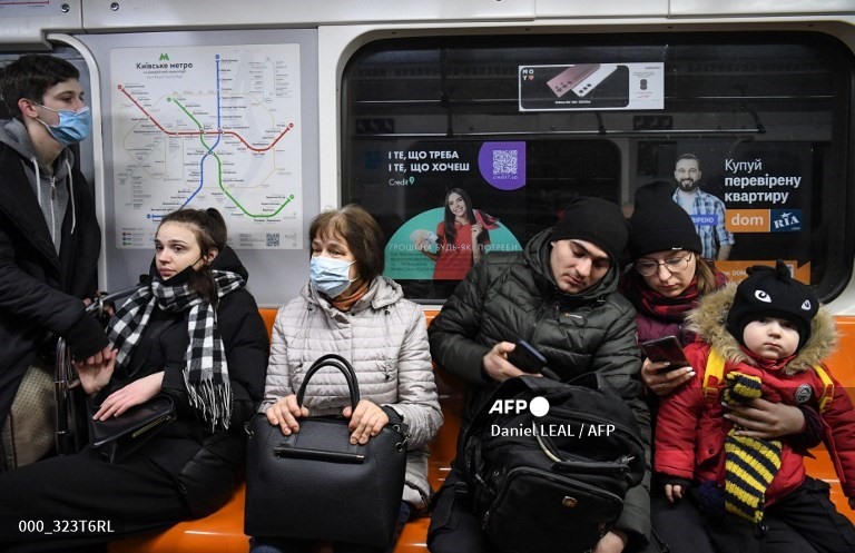 8. Mọi người, một số người mang theo túi xách và va li, ngồi trong một tàu điện ngầm ở Kyiv vào sáng ngày 24 tháng 2 năm 2022.