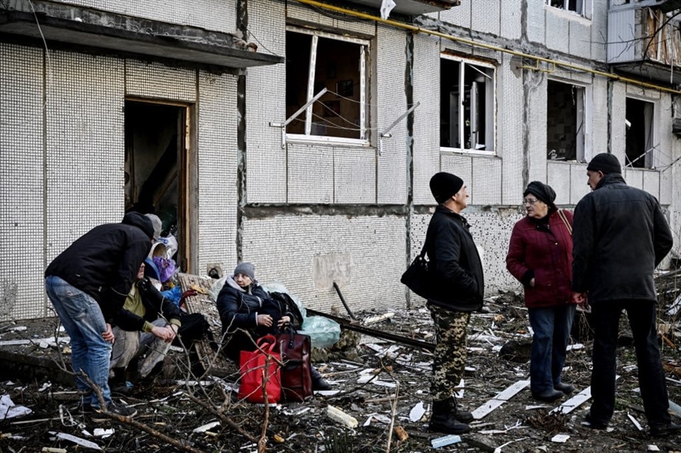 Người dân bên ngoài một tòa nhà bị phá hủy sau vụ bắn phá ở Chugiv, miền đông Ukraina ngày 24.2. Ảnh: AFP