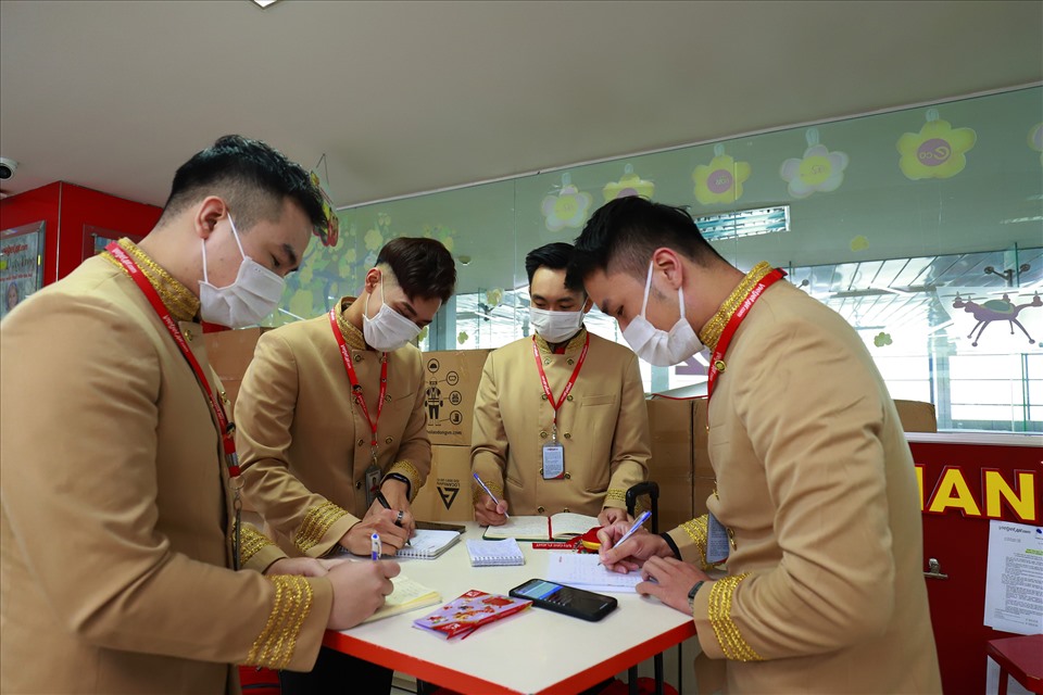 Anh Quang Huy (thứ 2), Quang Minh (thứ 4) cùng các đồng nghiệp trao đổi công việc trước chuyến bay từ Hà Nội đi Quy Nhơn sáng mùng 1 Tết. Ảnh: Đức Minh