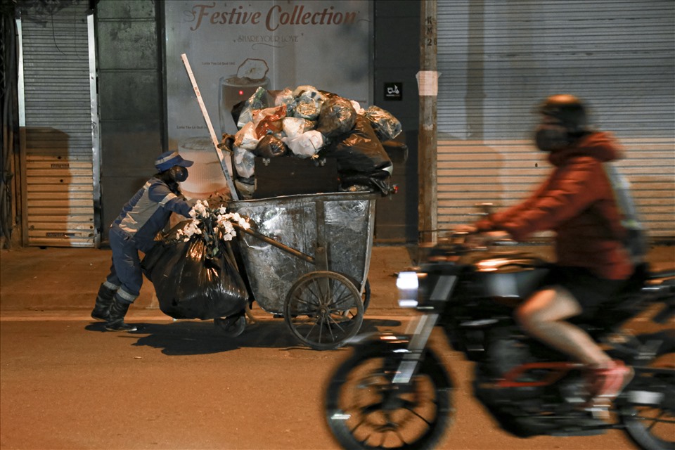 Những người công nhân lặng lẽ đẩy xe rác nặng nề trong đêm tối