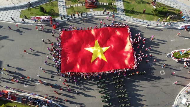 Ban tổ chức cùng các vận động viên tham dự Tiền Phong Marathon, người dân Côn Đảo cùng nhau trải lá cờ Tổ quốc rộng 300m2 trên Quảng trường Cột cờ. Ảnh: Như Ý