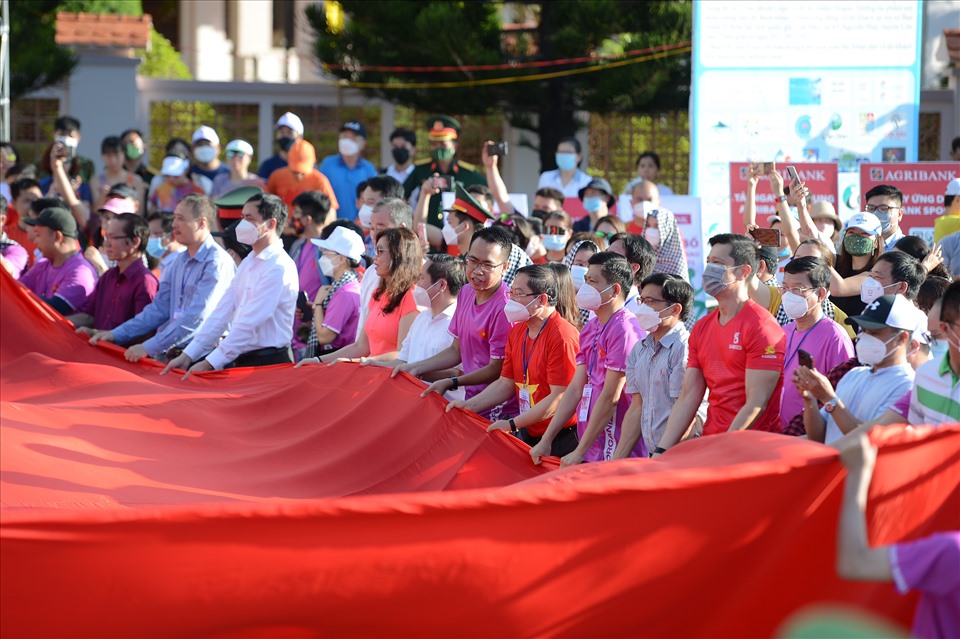 Ban tổ chức cùng các vận động viên tham dự Tiền Phong Marathon, người dân Côn Đảo cùng nhau trải lá cờ Tổ quốc rộng 300m2 trên Quảng trường Cột cờ. Ảnh: Như Ý
