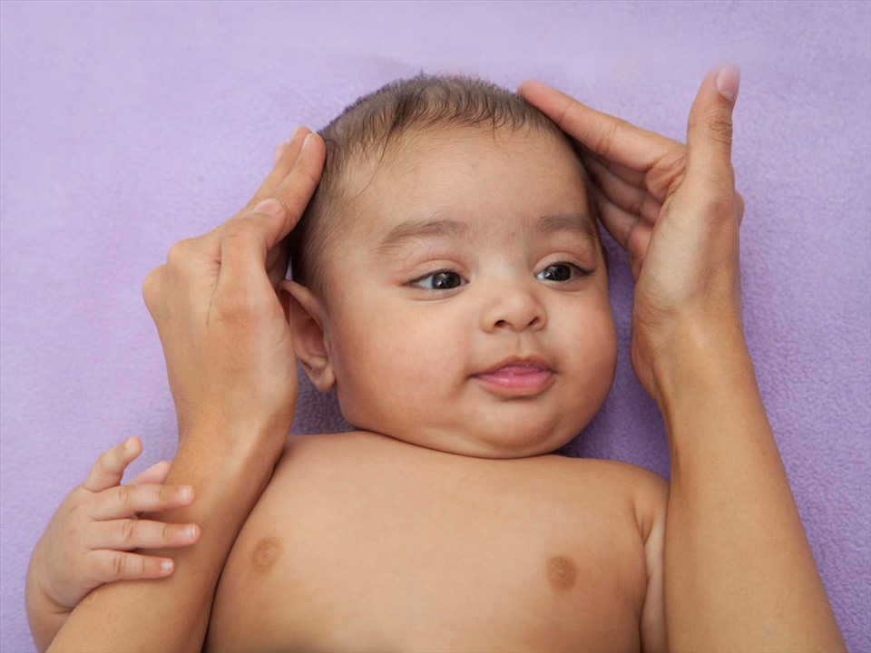 Massage da dầu cho trẻ sẽ giúp kích thích mọc tóc. Ảnh: Xinhua