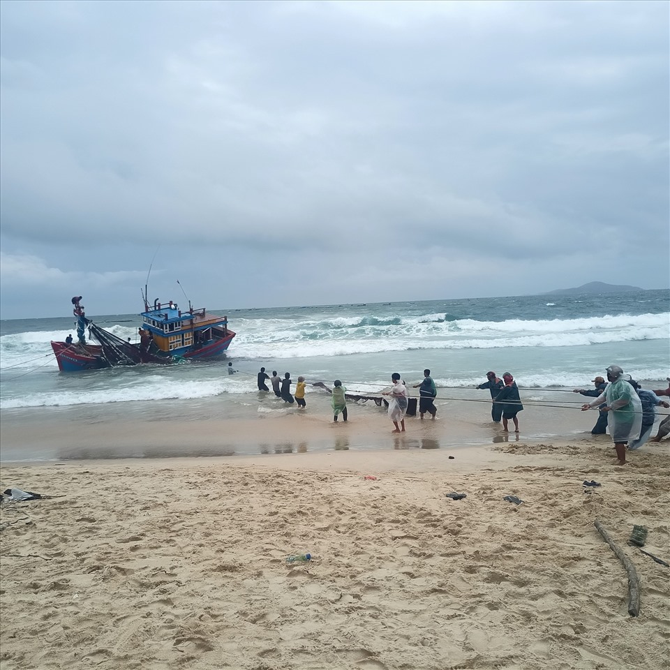 Người dân xã An Phú đang nỗ lực cứu tàu bị sóng đánh úp. Ảnh: Phương Uyên