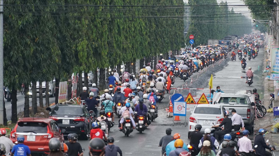 Tại đường Nguyễn Văn Cừ, các phương tiện nối tiếp nhau di chuyển chậm do mưa và làm đường.