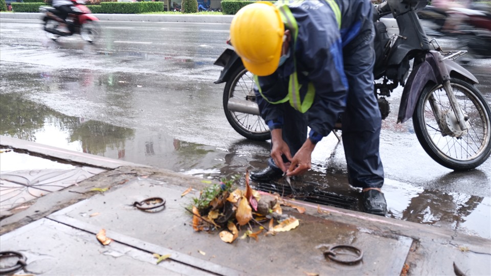 Trước tình trạng trên, nhiều nhân viên môi trường phải gấp rút khơi thông rác, lá cây rơi vào cống để nước kịp thoát.