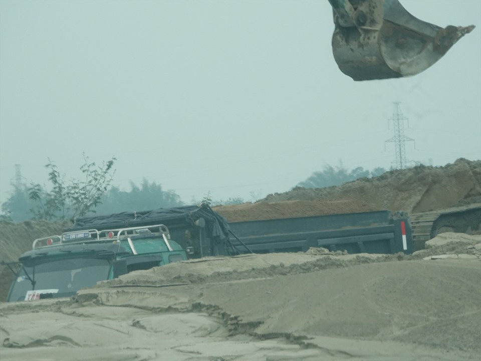 Máy xúc cát tràn thùng xe tải ở một mỏ cát bên sông Lam thuộc xã Xuân Lam. Ảnh: Trần Tuấn.