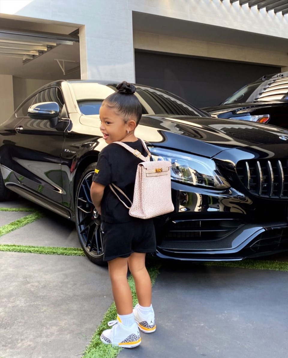 Bé Stormi diện đồ hiệu, đeo phụ kiện đắt tiền tạo dáng bên siêu xe của mẹ. Ảnh: Instagram.