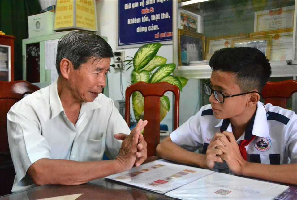 Ông Trần Hữu Huệ tận tình chỉ dẫn kiến thức về tem cho học sinh trong buổi sinh hoạt hằng tuần. Ảnh: LT