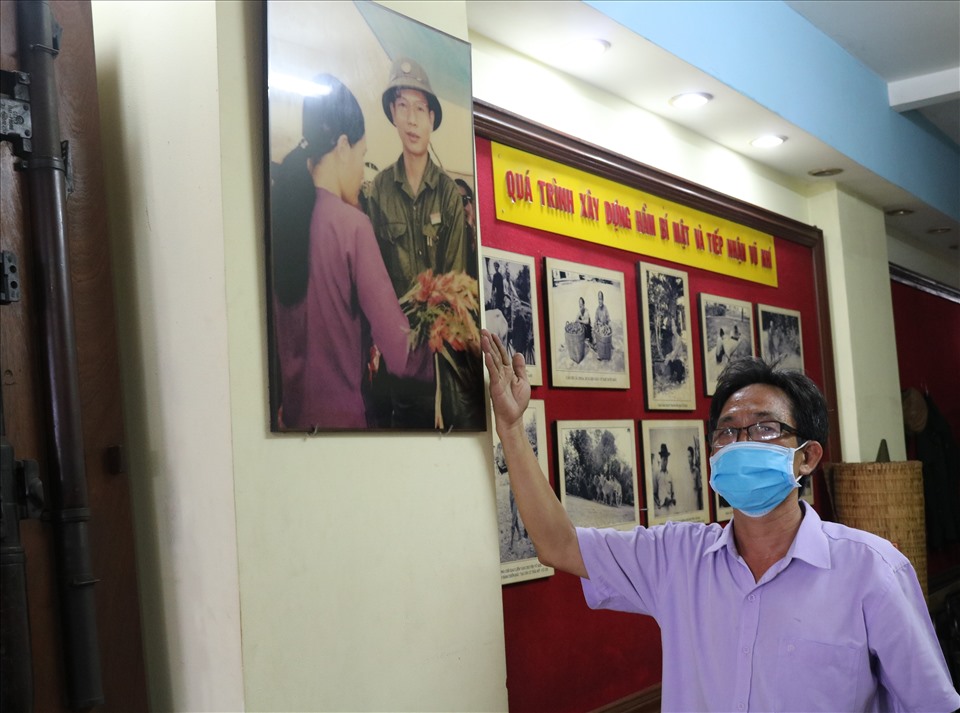 Ông Nguyễn Thanh Chi (57 tuổi, cựu chiến binh đang trông coi di tích) cho biết, căn nhà này được ông Trần Văn Lai (biệt danh Năm Lai, Mai Hồng Quế) mua vào năm 1965 cùng với hai căn ở hai bên. Vì nằm giữa, có diện tích nhỏ (dài 14,9m, rộng 2,5m), có hai mặt tiền nên vợ chồng ông chọn để đào hầm bí mật. Trong ảnh, ông Chi đang chỉ tay về hình ảnh ông Năm Lai - chiến sỹ biệt động Sài Gòn gan dạ, chủ nhân căn hầm bí mật chứa hơn 2 tấn vũ khí.