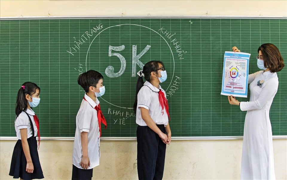 Cô giáo Ngô Thị Mai Trang trong tà áo dài đang hướng dẫn các em học sinh trường tiểu học Gia Thụy, Hà Nội, Việt Nam 5 biện pháp phòng chống đại dịch COVID-19.