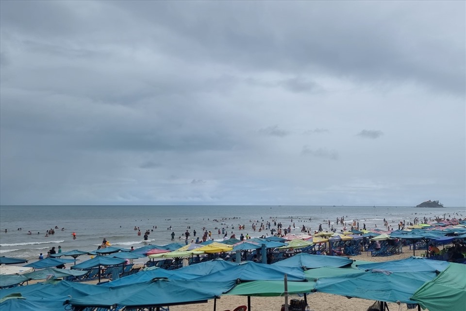 12h trưa, trời mưa phùn nhẹ nhưng nhiều du khách vẫn chọn ở dưới bãi biển vui chơi. Ảnh: T.A