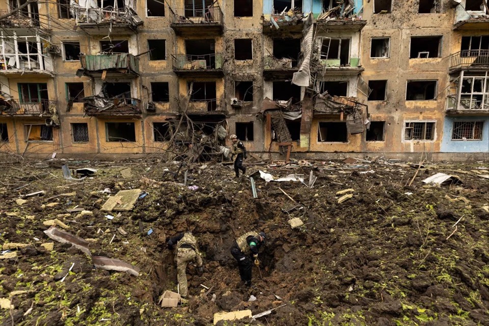 Các nhân viên quân sự Ukraina kiểm tra địa điểm xảy ra vụ tấn công bằng tên lửa trước một tòa nhà dân cư bị hư hại ở Dobropillia, thuộc vùng Donetsk, Ukraina, ngày 30.4.2022. Ảnh: Reuters
