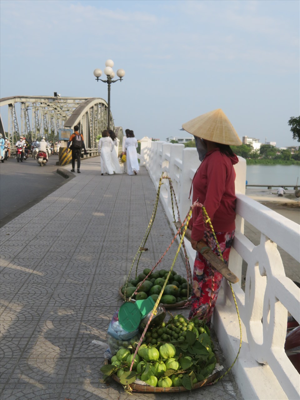 Những người phụ nữ từ Hà Nội vào Huế nhân dịp lễ 30.4- mùng 1.5, mang theo bó hoa loa kèn làm “đạo cụ” - chụp ảnh trên cầu Tràng Tiền và những người đàn bà Huế tần tảo hàng rong.